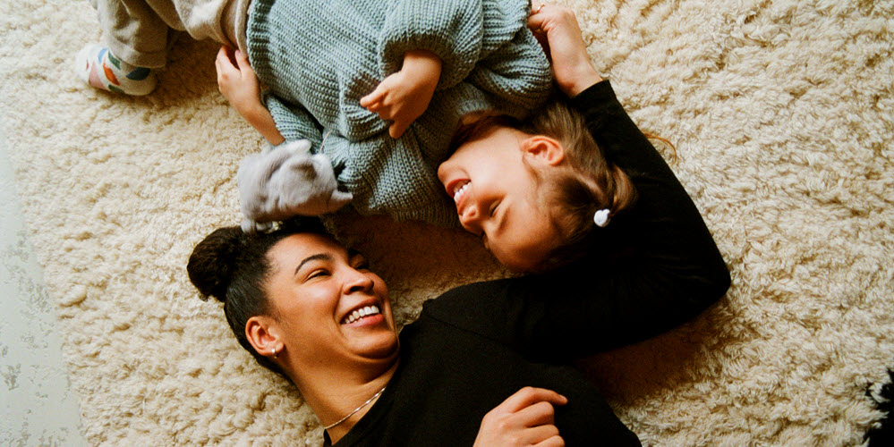 Woman and child laying on carpet smiling