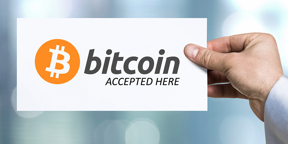 Hand holding piece of paper with inscription Bitcoin accepted here.