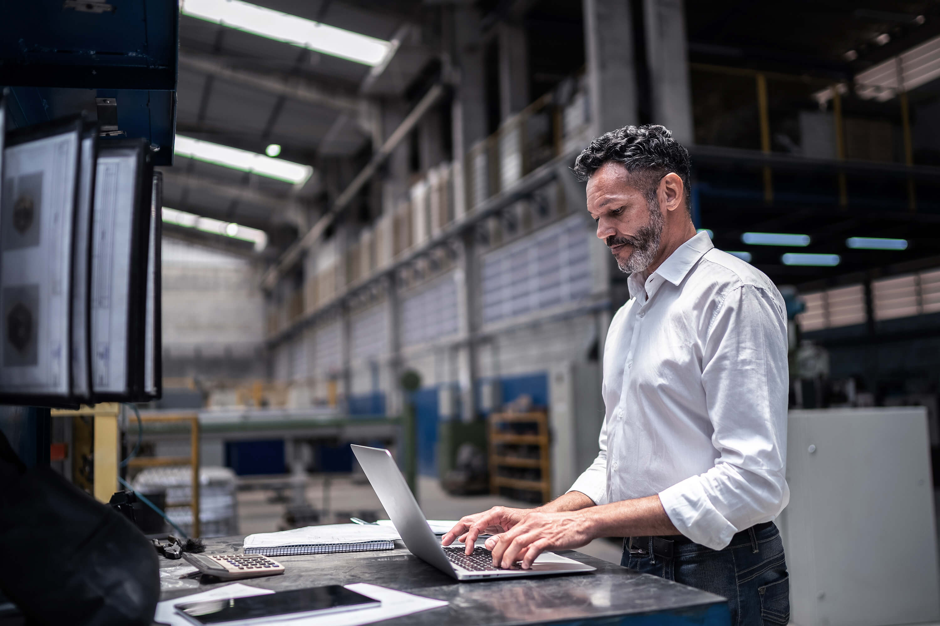 Man typing at laptop in warehouse