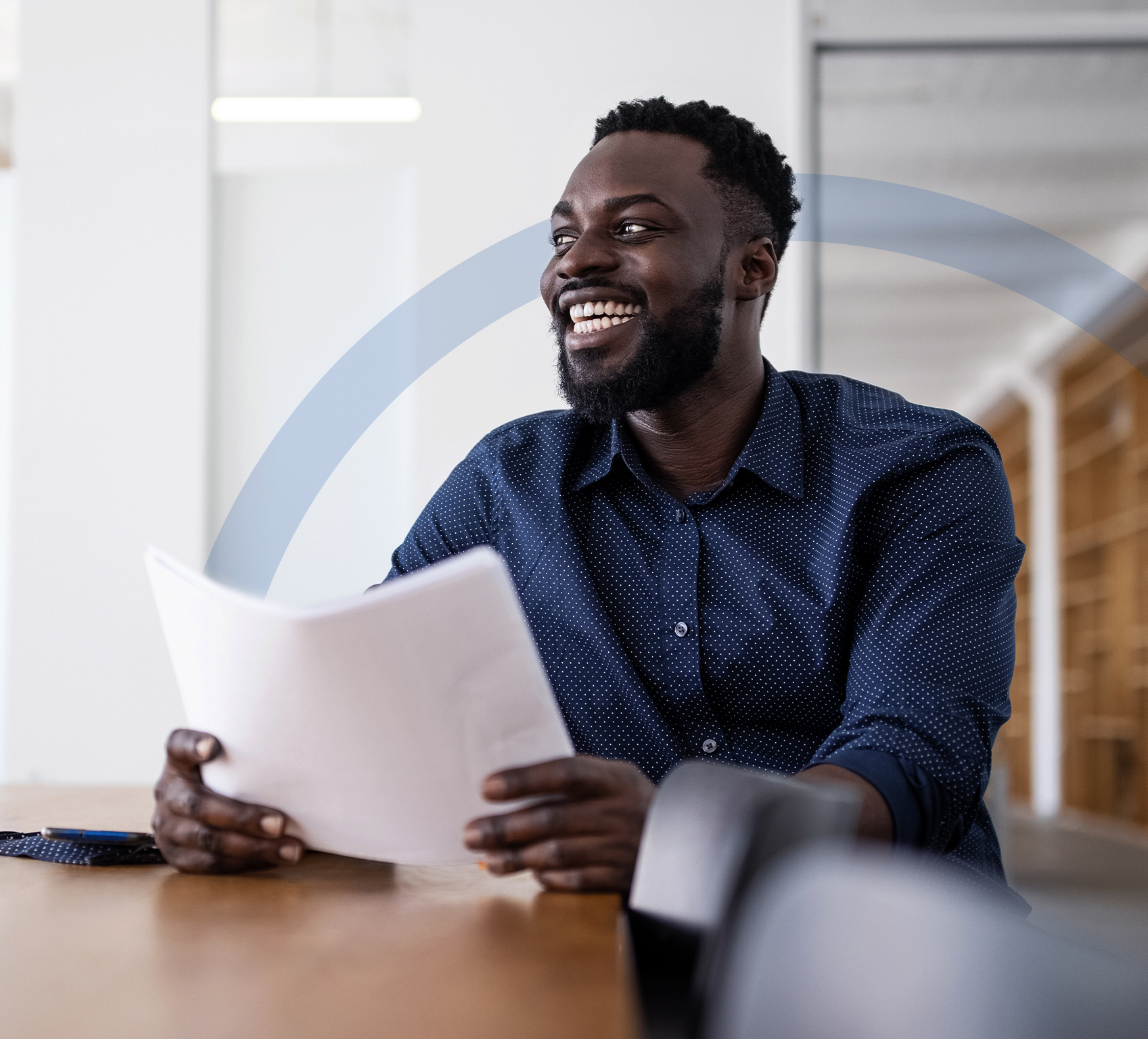 Man sitting at desk smiling with papers