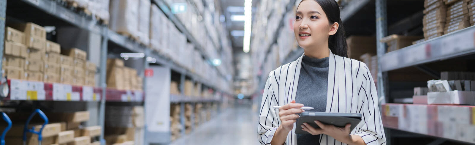 Woman checking off inventory in a warehouse.