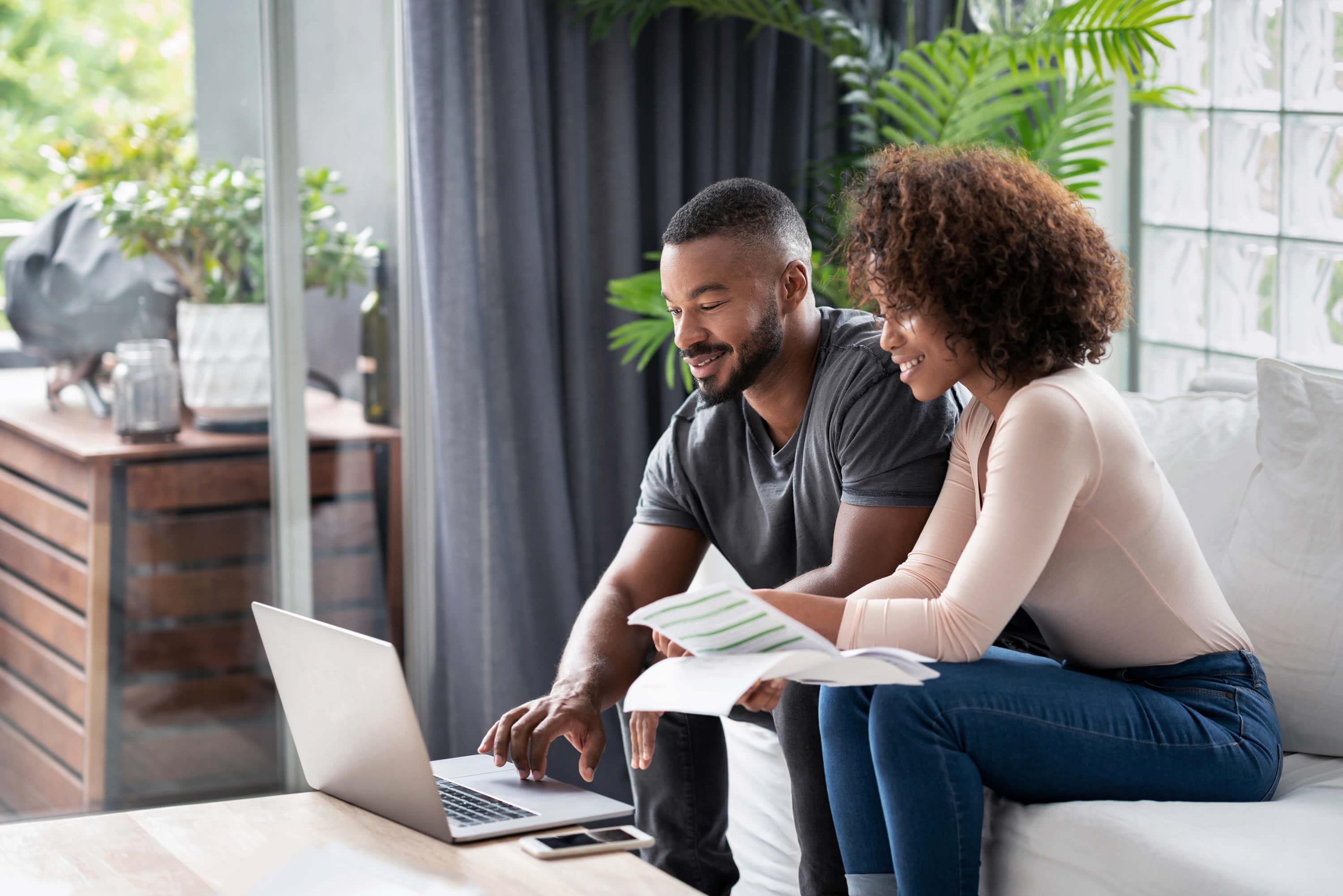 Couple looking over bank statements on laptop.