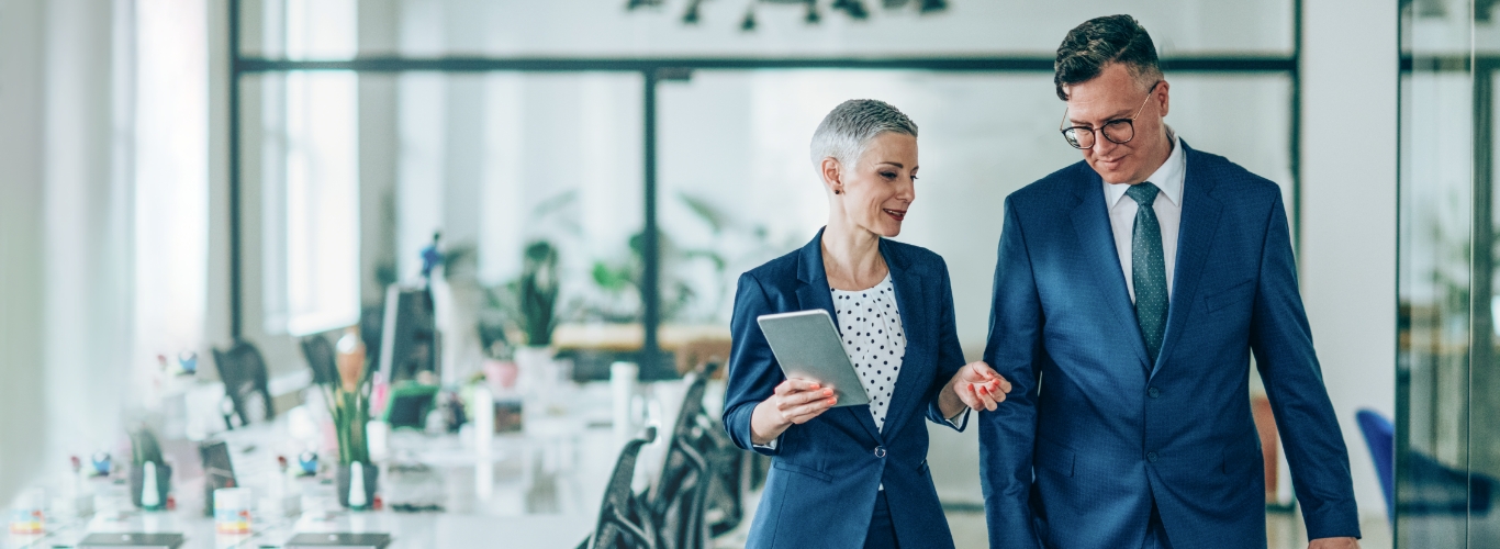 Woman and man talking together while walking in office 