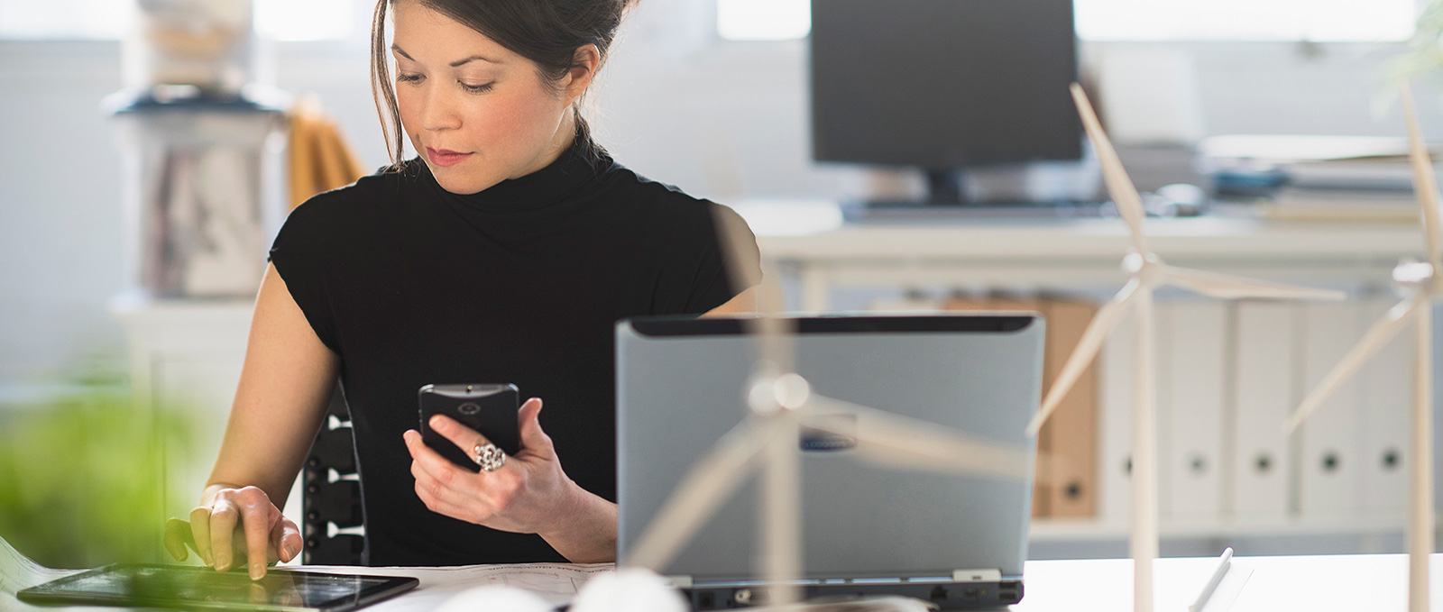 A woman working with a tablet, phone and laptop.