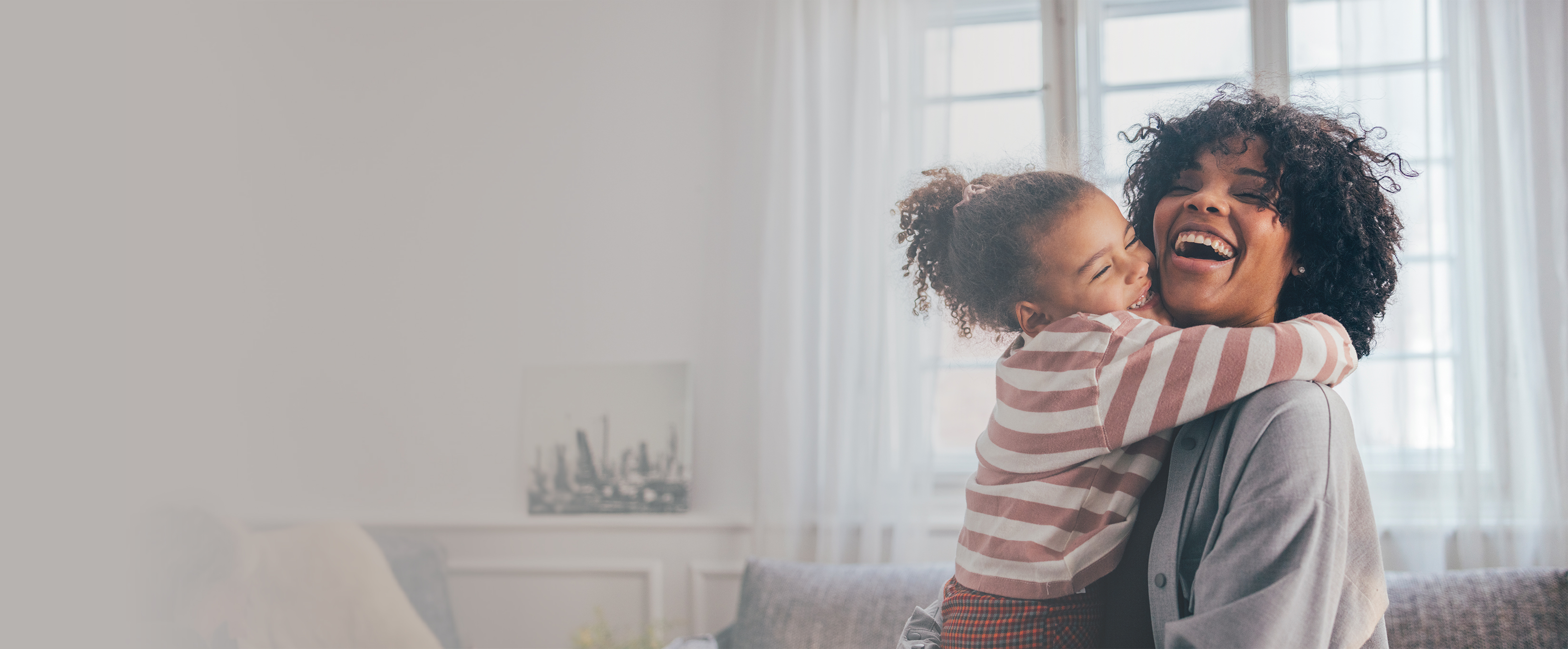 A happy woman at home being hugged by her smiling daughter.